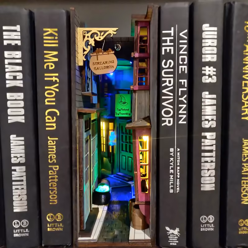 A diorama of a small alley on a shelf nestled between 5 books.