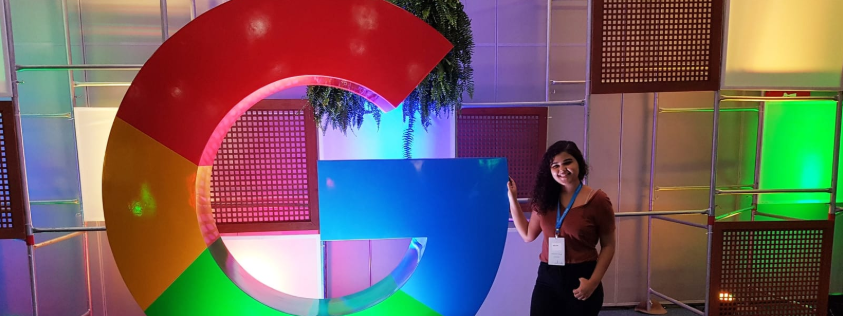 Uma foto minha posando ao lado de uma estátua do Google.