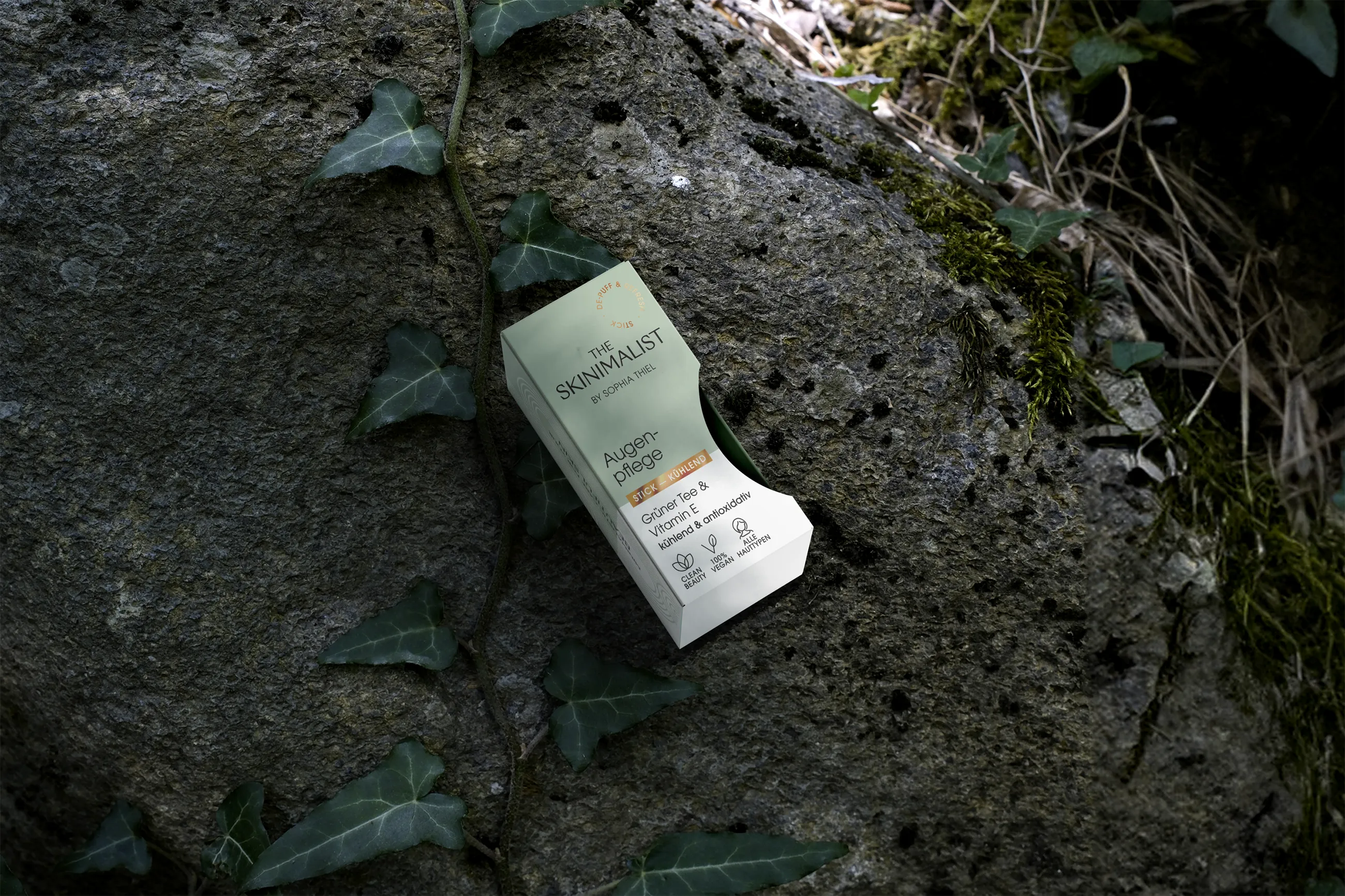Verpackung von The Skiniminalist Augenpflege mit grünem auf einem moosbedeckten Felsen mit Efeu.