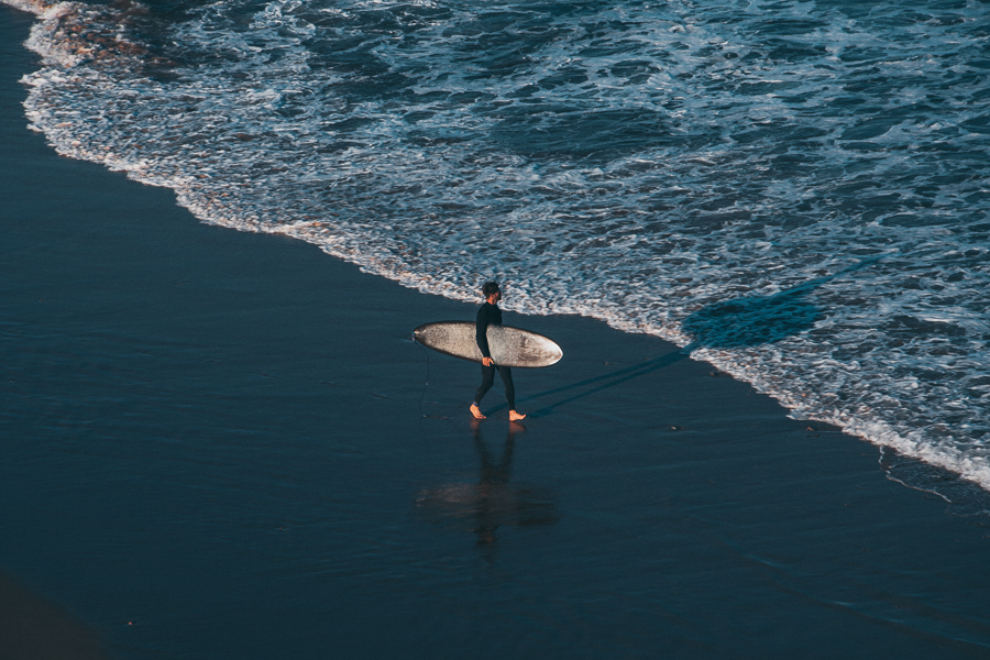 A surfer walking towards the ocean in Arrifana beach Algarve Portugal