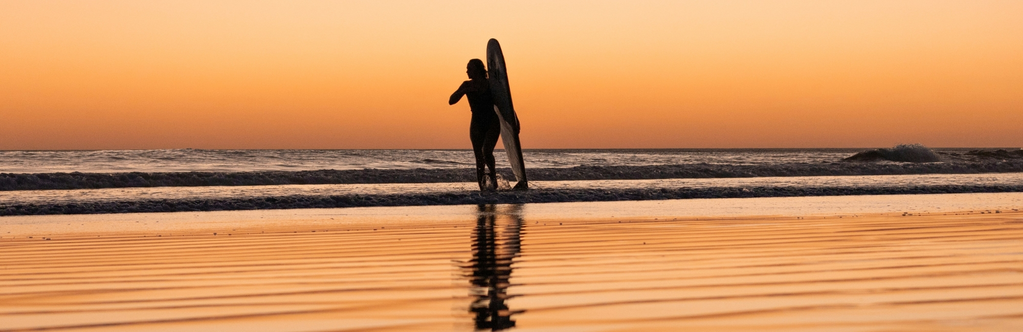 surfer girl going for a sunset surf session in nicaragua