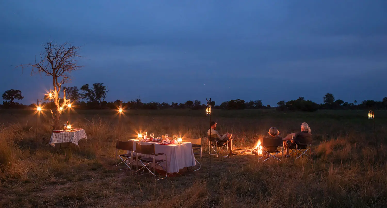 People sitting around a boma fire in the african savannah
