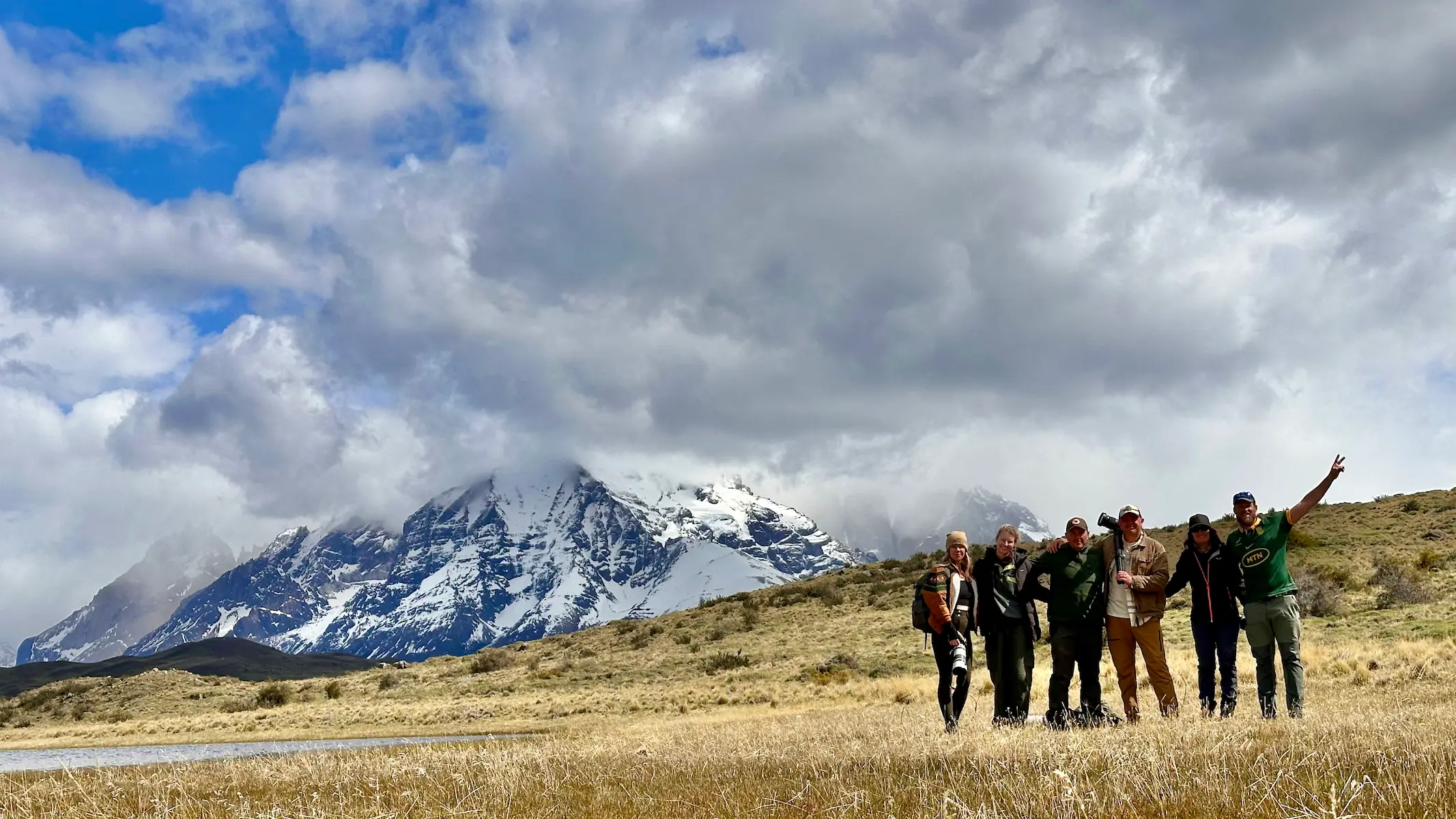 WWW Travelers and Nick standing on a grassy plain in front of the Torres del Paine mountains