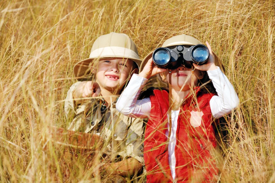 two children sitting in tall grass on safari