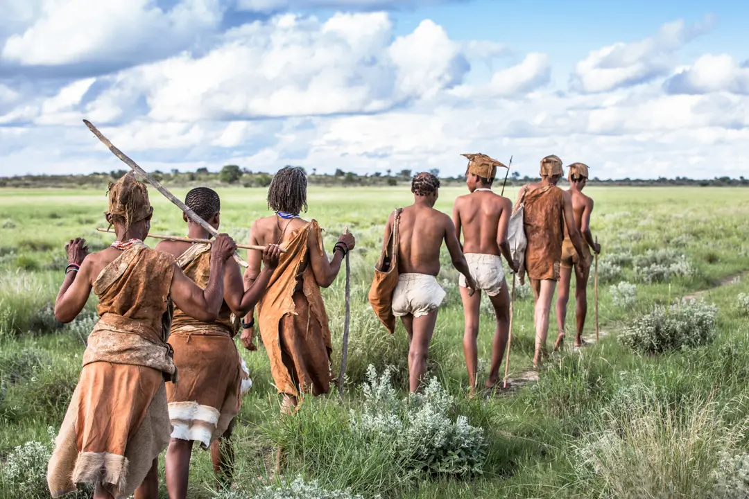 San bushmen walking in a line across plains