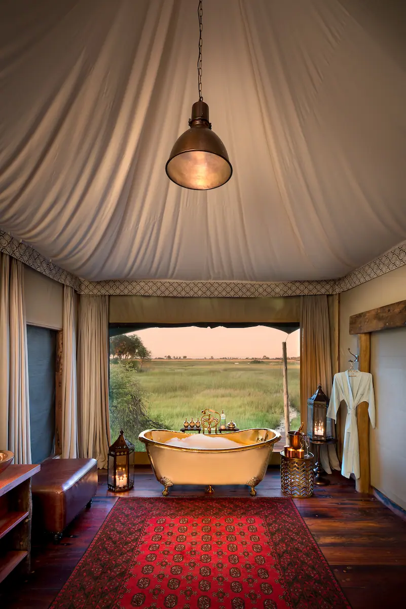 Brass freestanding bath in a canvas guest tent bathroom overlooking the Okavango floodplain at Duba Plains, Botswana