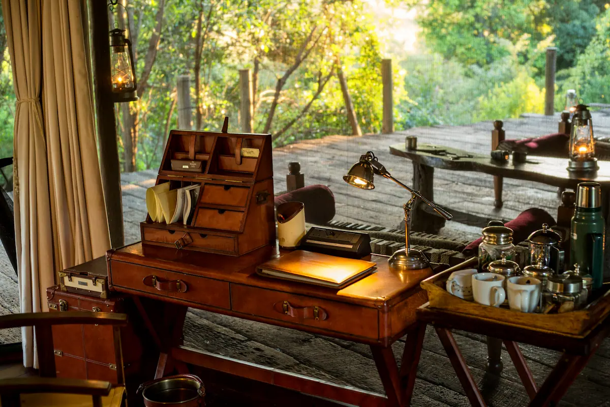Leather campaign desk, brass lamp and lanterns on a timber deck at Mara Plains Camp, Maasai Mara, Kenya