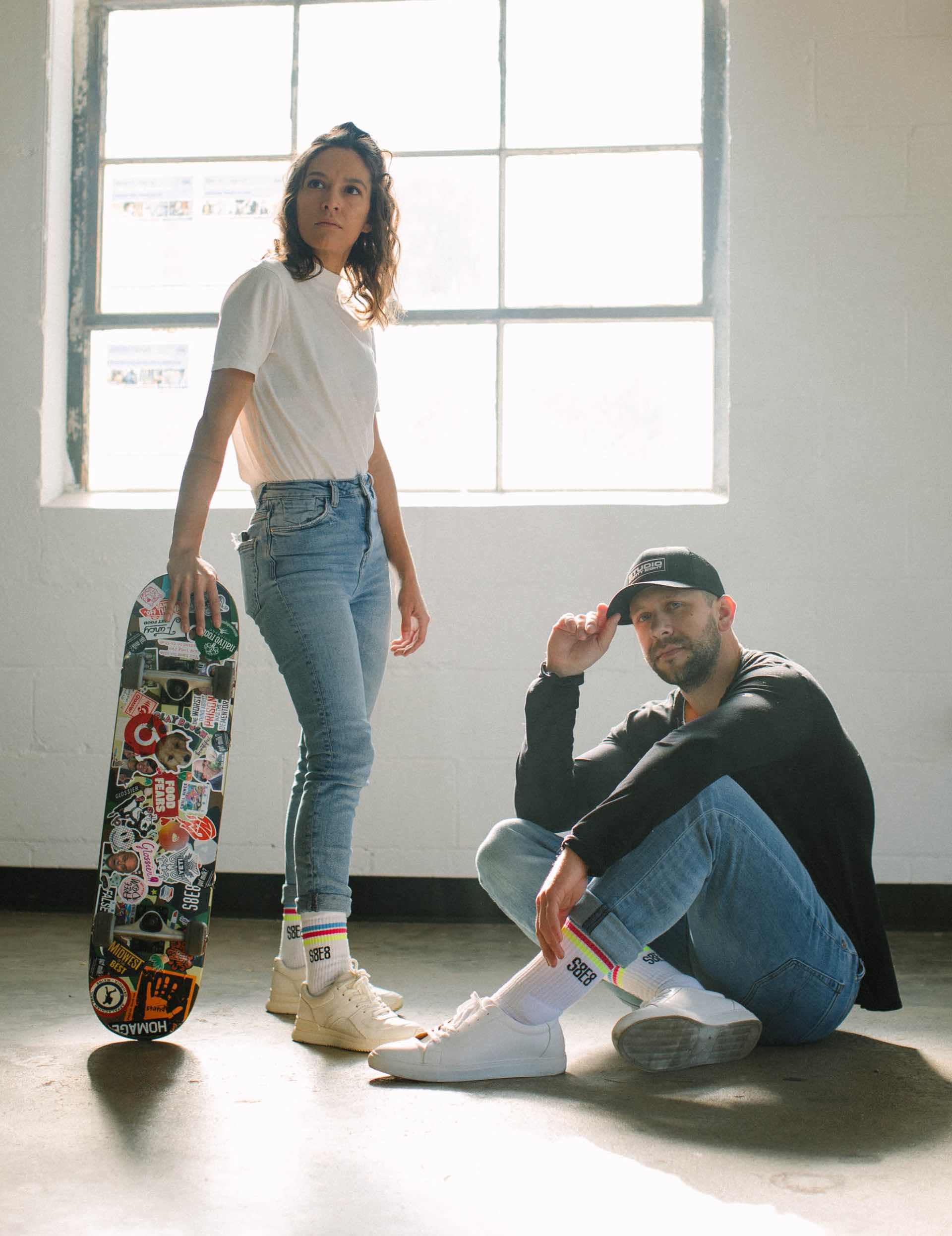 Photo of Janet wearing S8E8 socks and Tanner wearing S8E8 socks and a black S8E8 hat