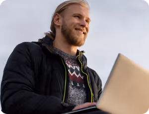 A bearded man focused on his laptop, engaged in work or study, with a thoughtful expression on his face.