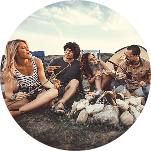 A group of people gathered around a campfire, sharing stories and enjoying the warmth of the flames in a nighttime setting.