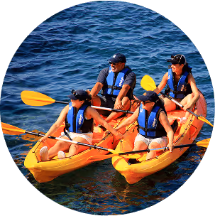 Three people paddling together in a kayak on a calm body of water, enjoying a sunny day outdoors.