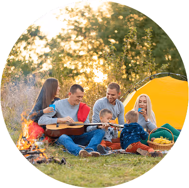 A family gathered around a campfire, one member playing guitar while others enjoy the outdoor camping experience.