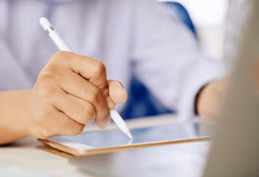 Hand holding a stylus signing on a tablet screen, representing AutoWaivers’ digital waiver signing feature