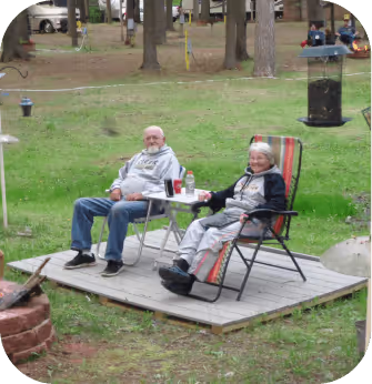 Two elderly individuals seated comfortably in lawn chairs, enjoying a peaceful moment outdoors.