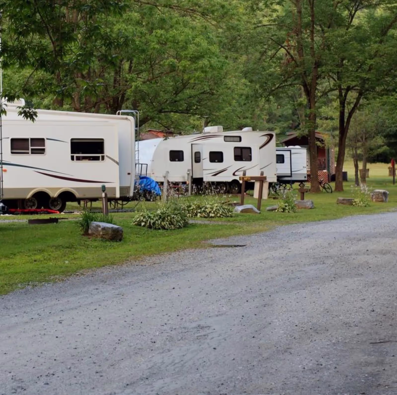 A row of RV parks situated along a dirt road, showcasing various recreational vehicles parked in a scenic setting.