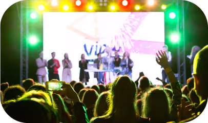 A lively crowd at a concert, with enthusiastic attendees raising their hands 