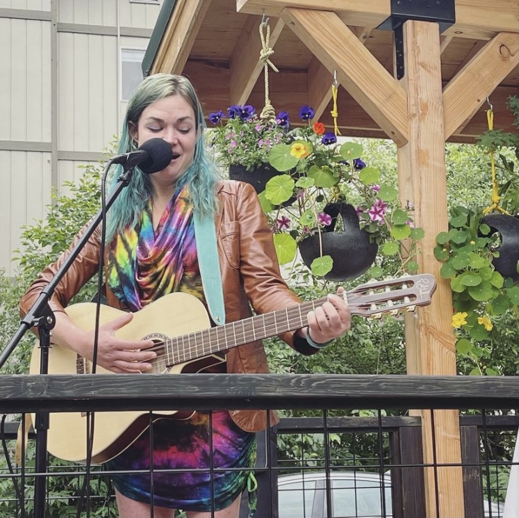 A woman playing a guitar on a porch.Spoonline Bistro Girdwood Alaska