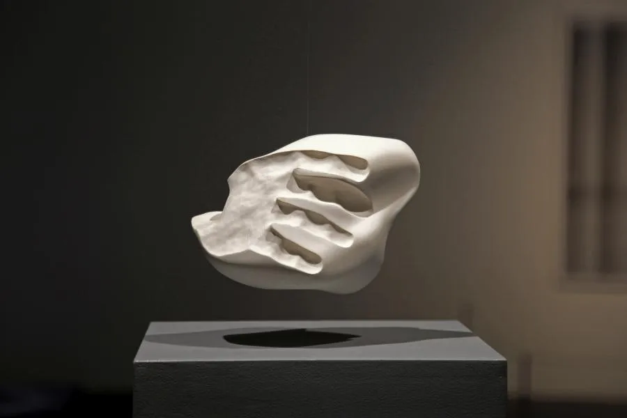 Sculptural artwork. A white ceramic blob that visualize the negative space between an handshake