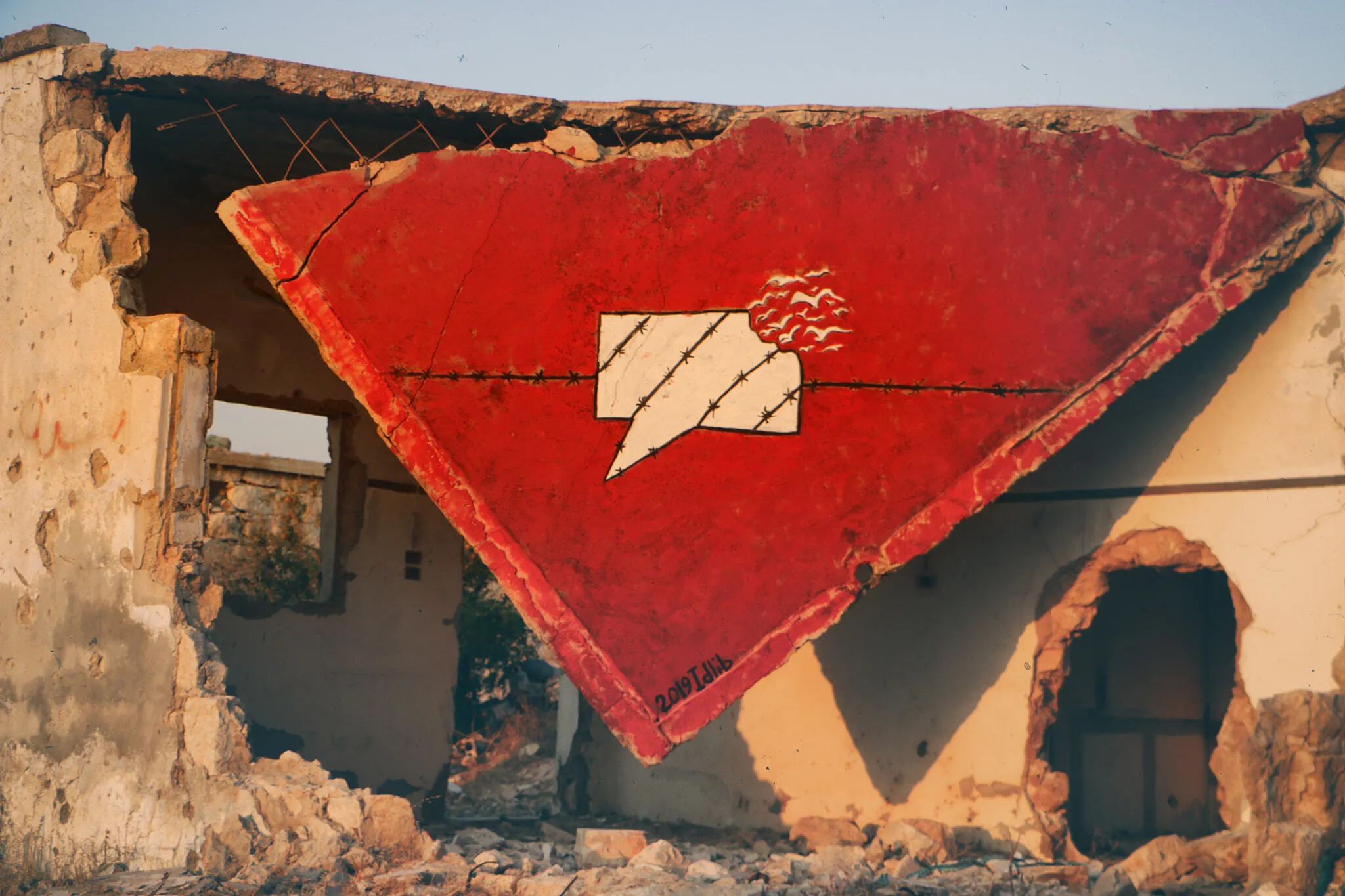 A graffiti in Syria. Red background with a speech bubble forced into barbed wire