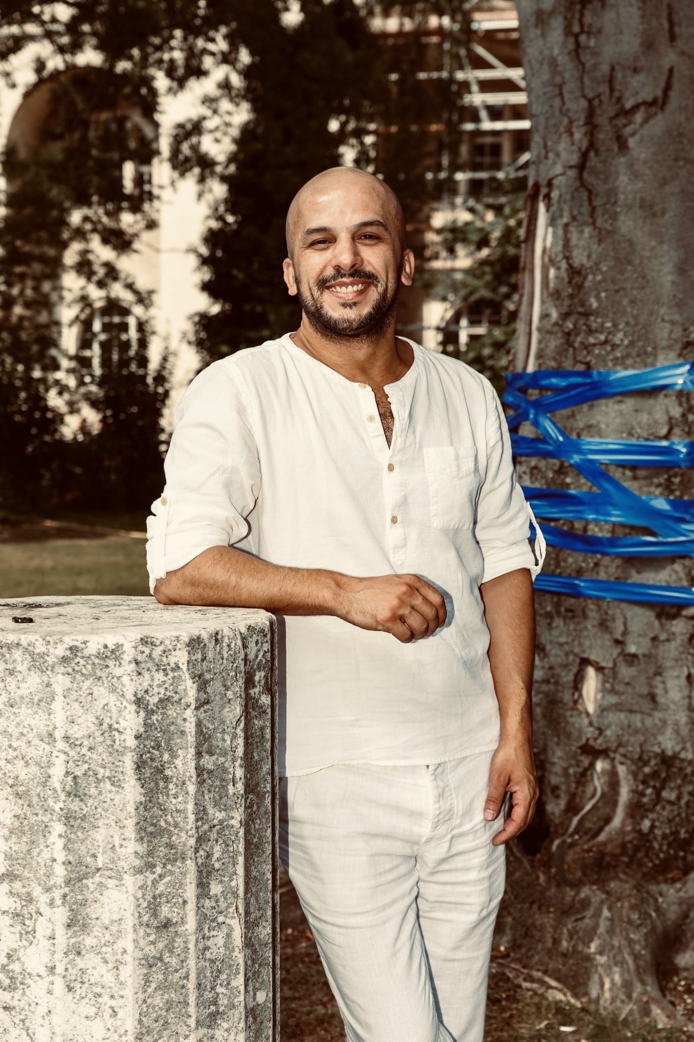 Potrait of Khaled. Full figure, leaning againsta column, dressed all in white