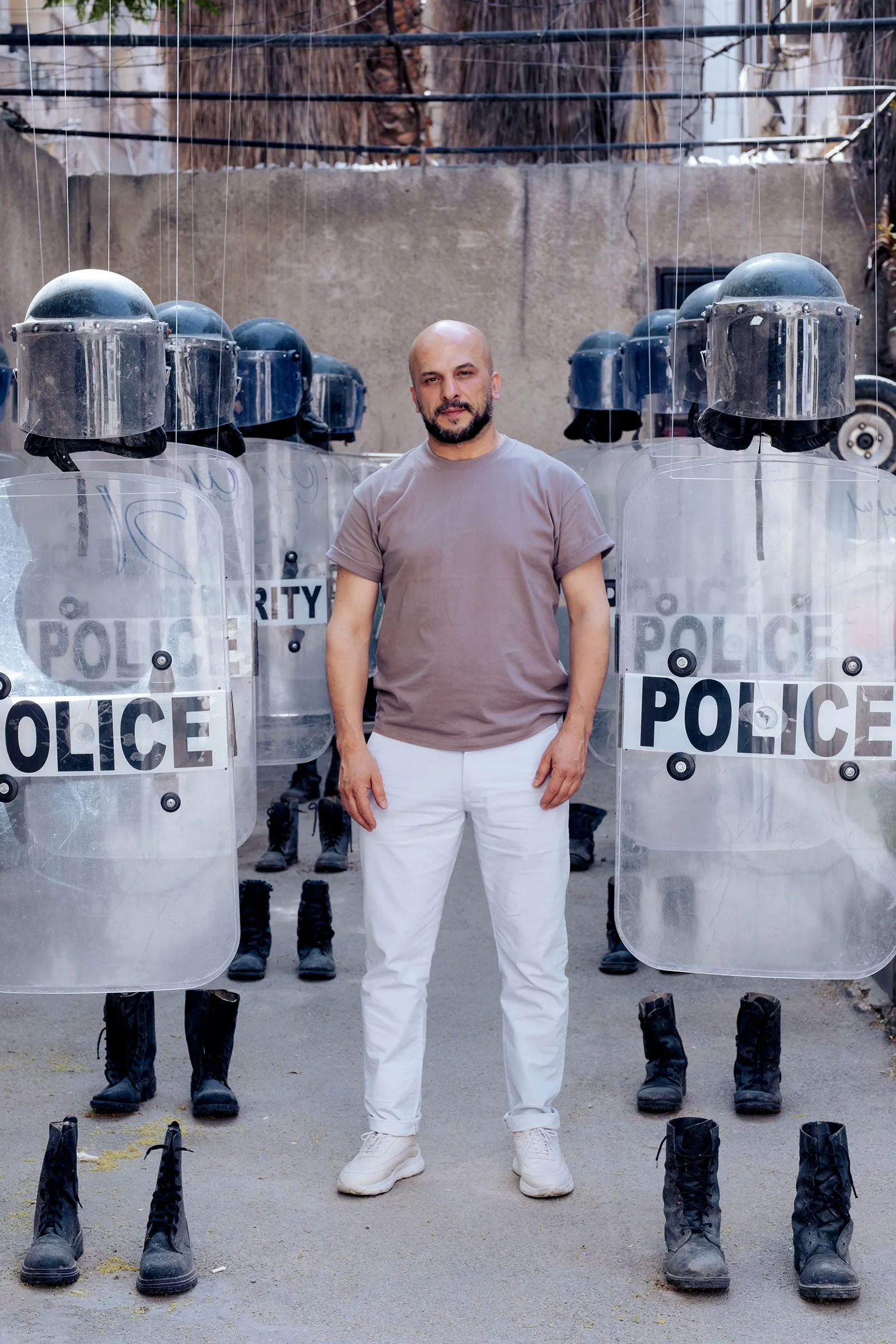 Portrait of Khaled Barakeh, standing full-length and leaning against a column, dressed in white.