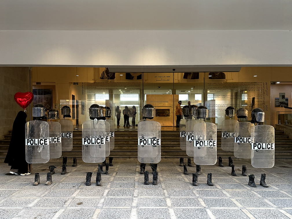 Anatomy of Fragility by Khaled Barakeh, front view of the installation with riot shields, helmets and boots arranged as absent bodies.