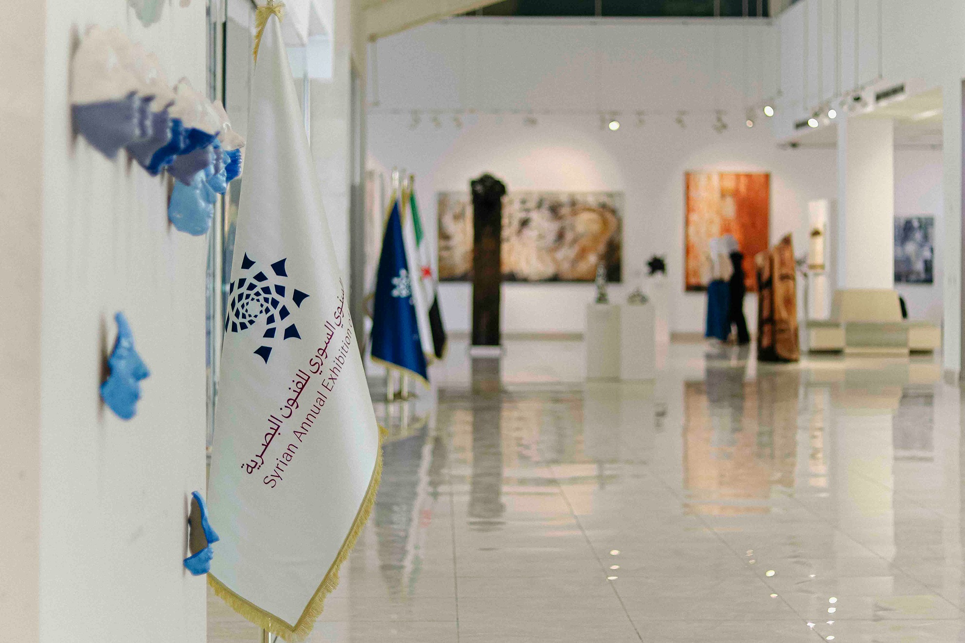 View into Art Leaves Its Mark through the exhibition entrance, with flags in the foreground. Photograph by Jawad Allazkani.
