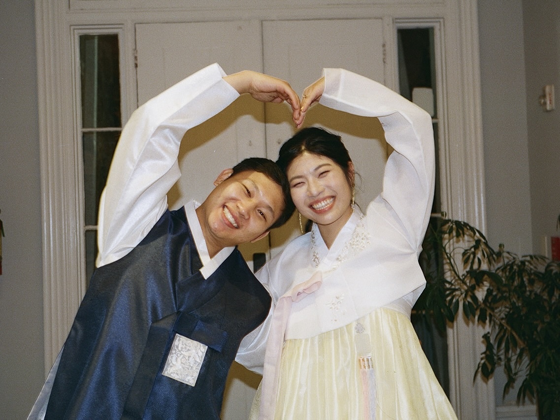 A bride and groom playfully use their arms to make a heart with each other during reception at Portico Awbury Arboretum.