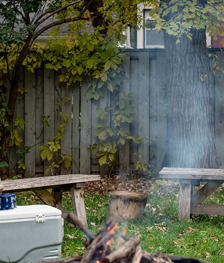 A fire pit emits smoke in a back yard.