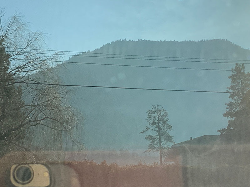 A haze of wood smoke hangs in the air with mountains in the distance.