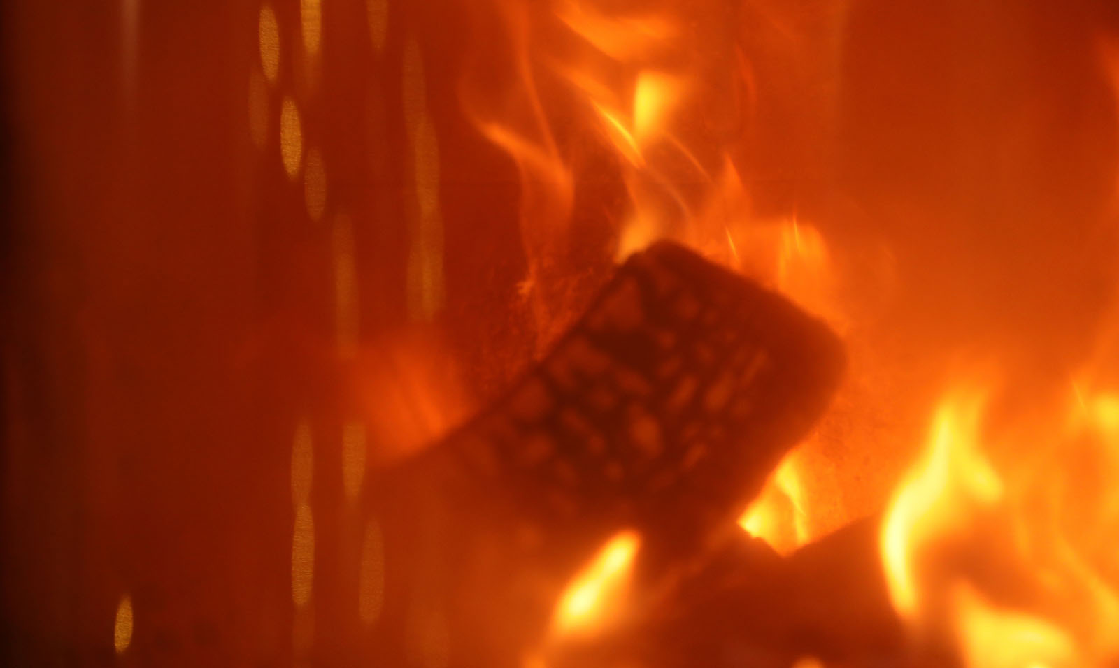 A fire burns inside a wood stove. The view is a closeup near the glass.