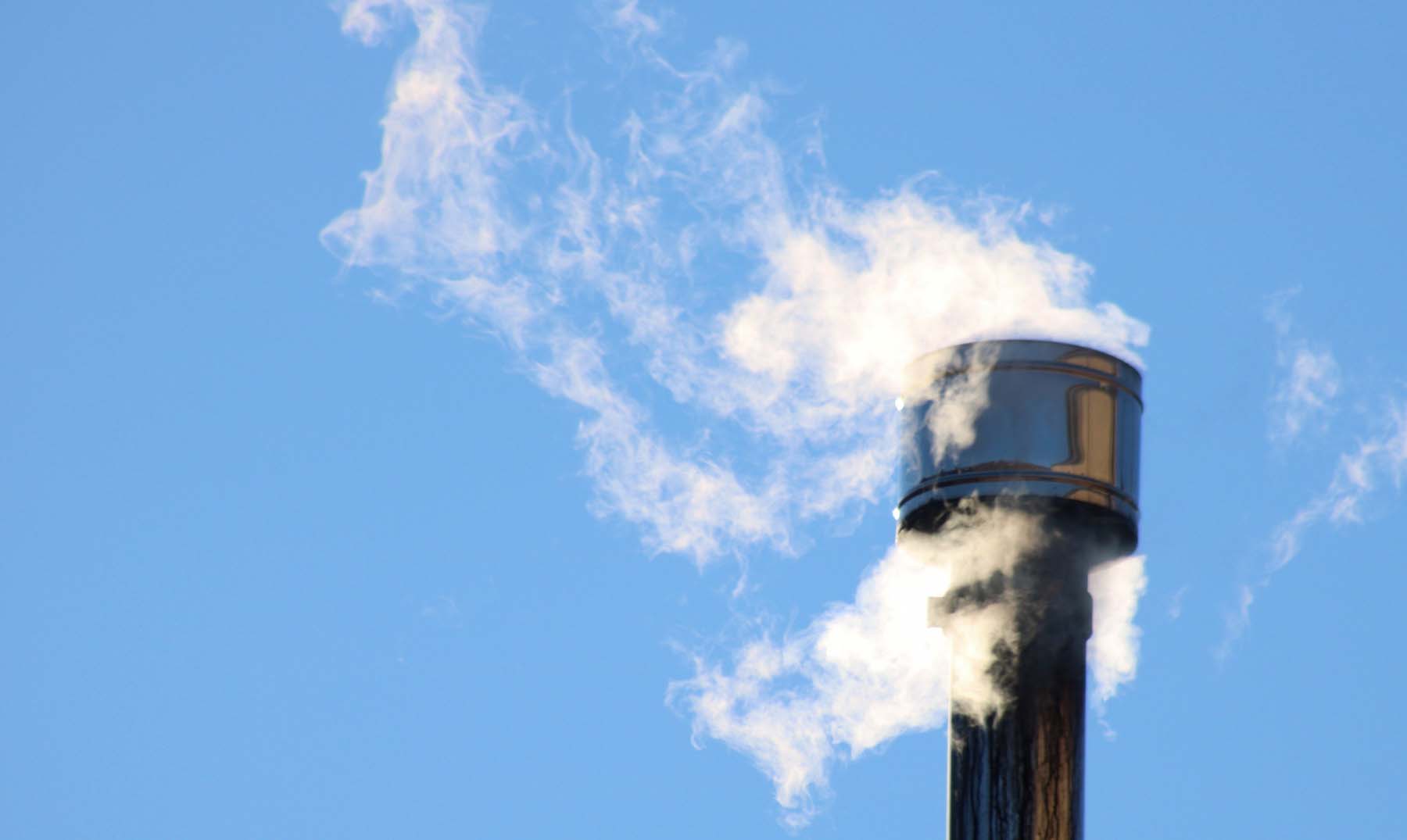 Smoke rises from a metal wood stove chimney.