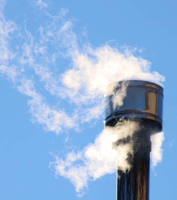 Smoke rises from a metal wood stove chimney.