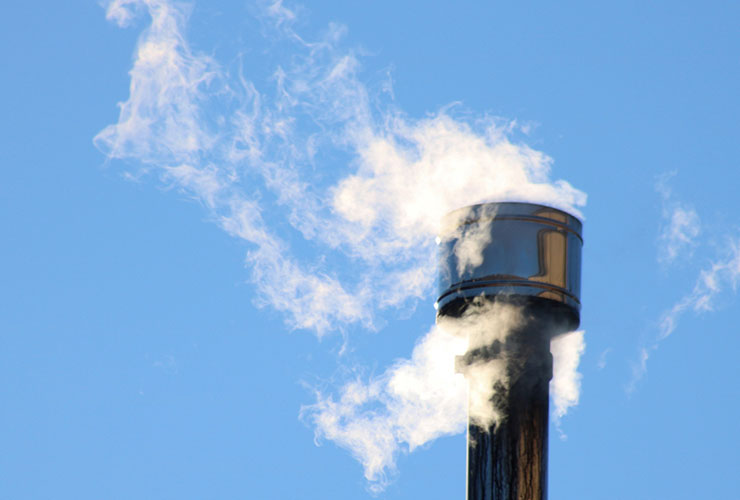 Smoke rises from a metal wood stove chimney.