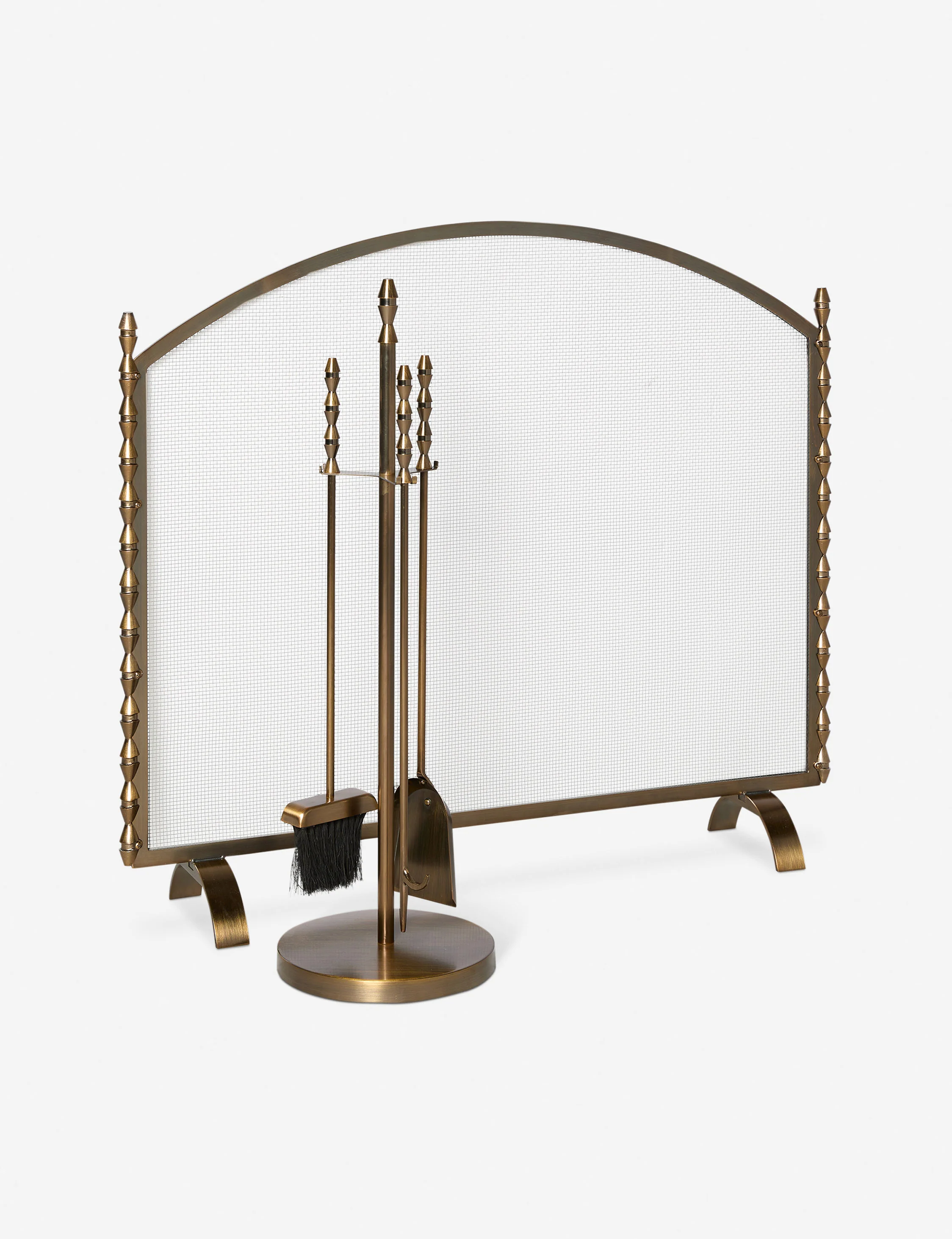 Bronze fireplace screen with decorative finials and a matching set of fireplace tools including a brush and shovel on a stand.