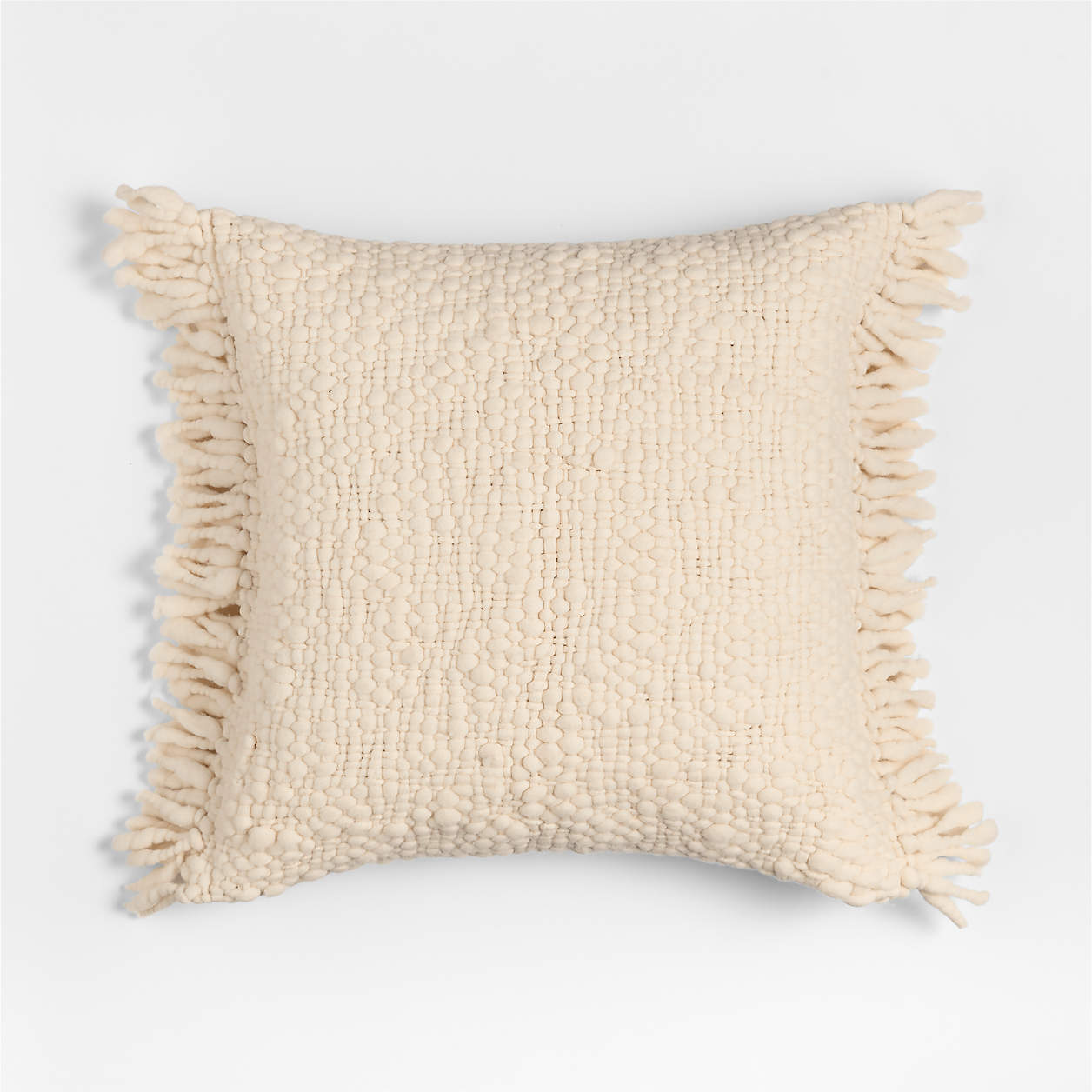 Square cream-colored textured pillow with fringe on all sides.