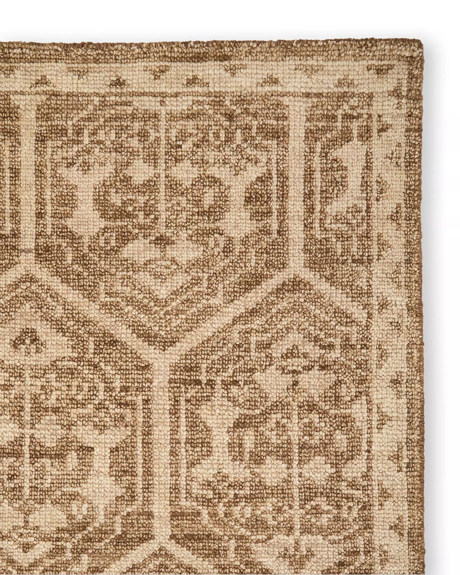 Close-up of a brown and beige wool rug with hexagonal and floral geometric patterns.