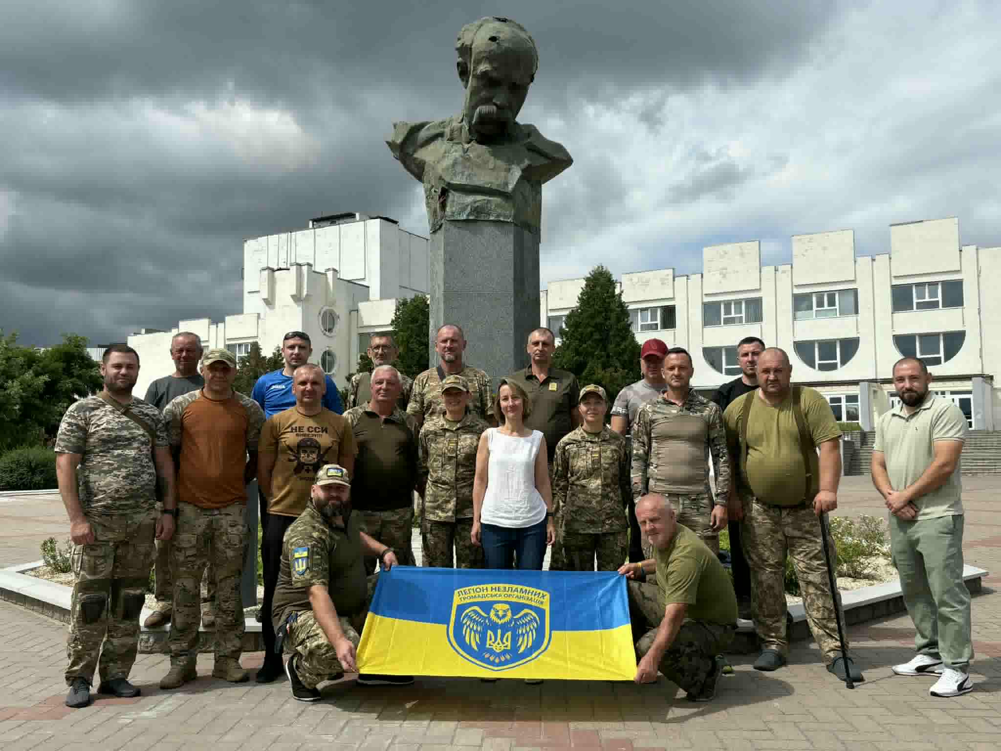 a group of people holding a flag in front of a statue