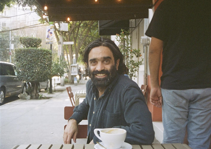 a photo of Sorab Mohebbi sitting at a table outside with a cup of coffee in front of him