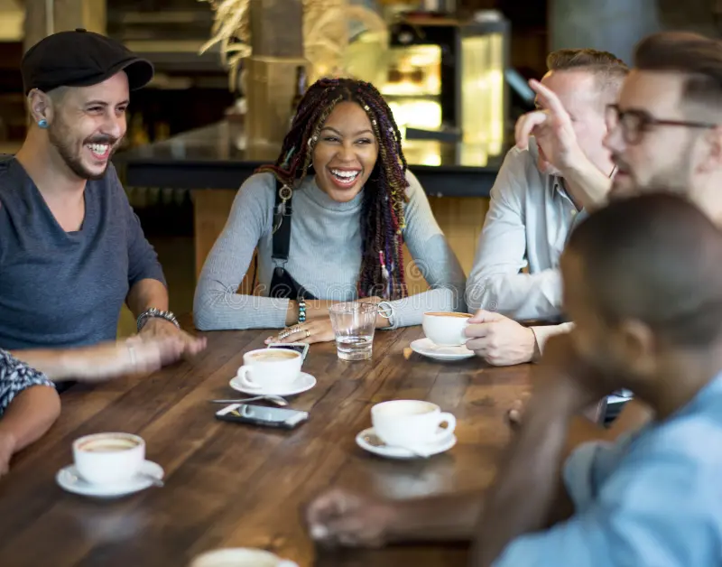 people gathered around a table with coffee and talking and laughing