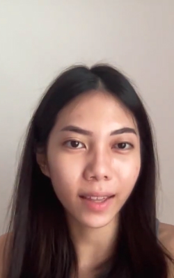 Close-up of a young woman with long dark hair speaking against a plain light background.