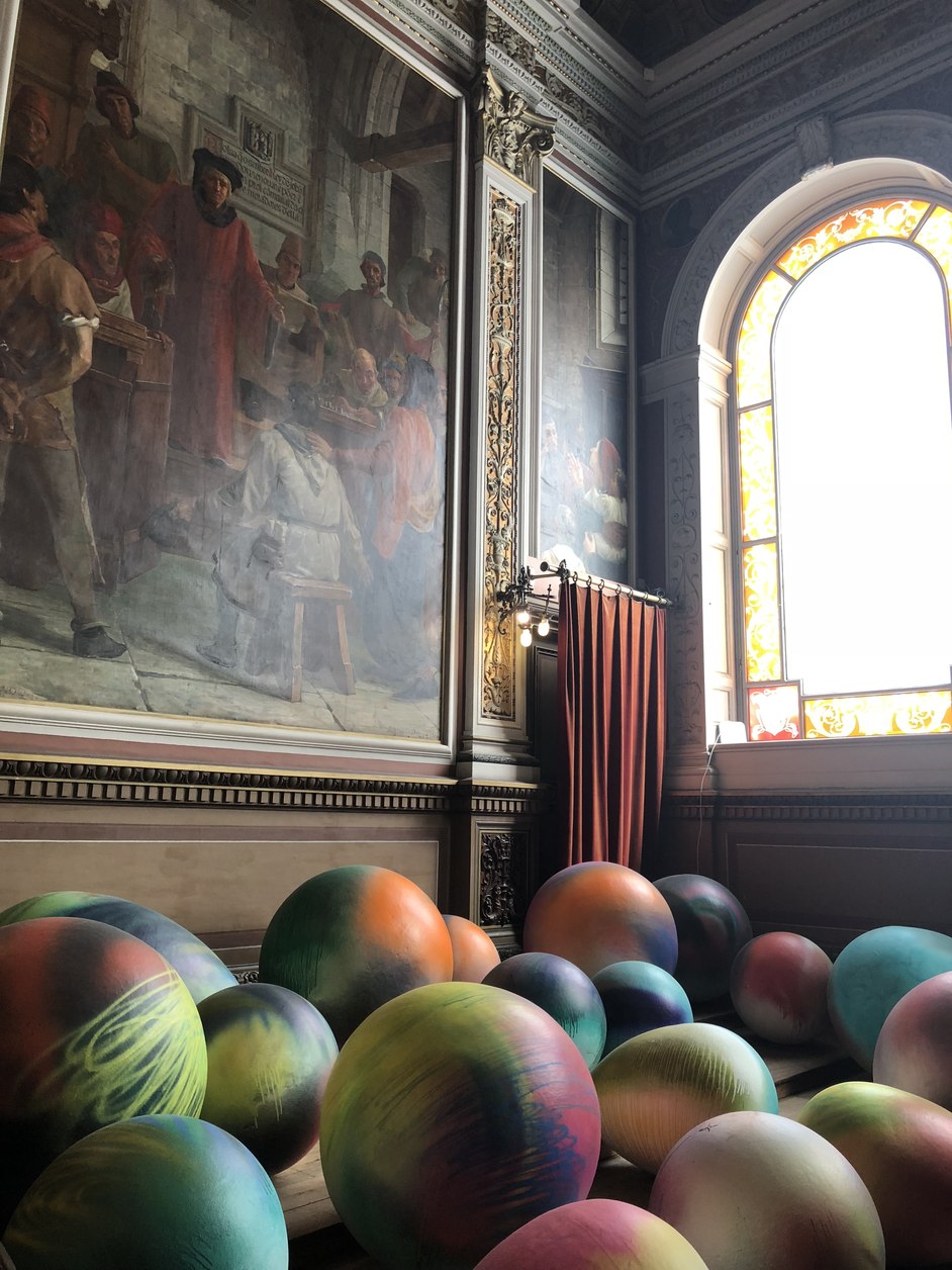 Painted hall with a stained glass window and glazed spheres on the floor