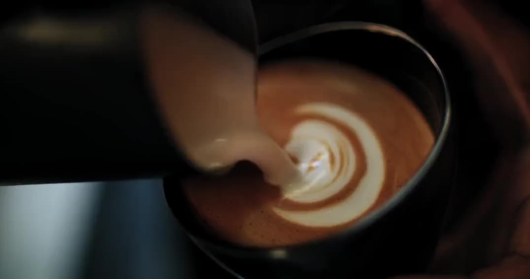 Milk poured into coffee, forming a rosetta