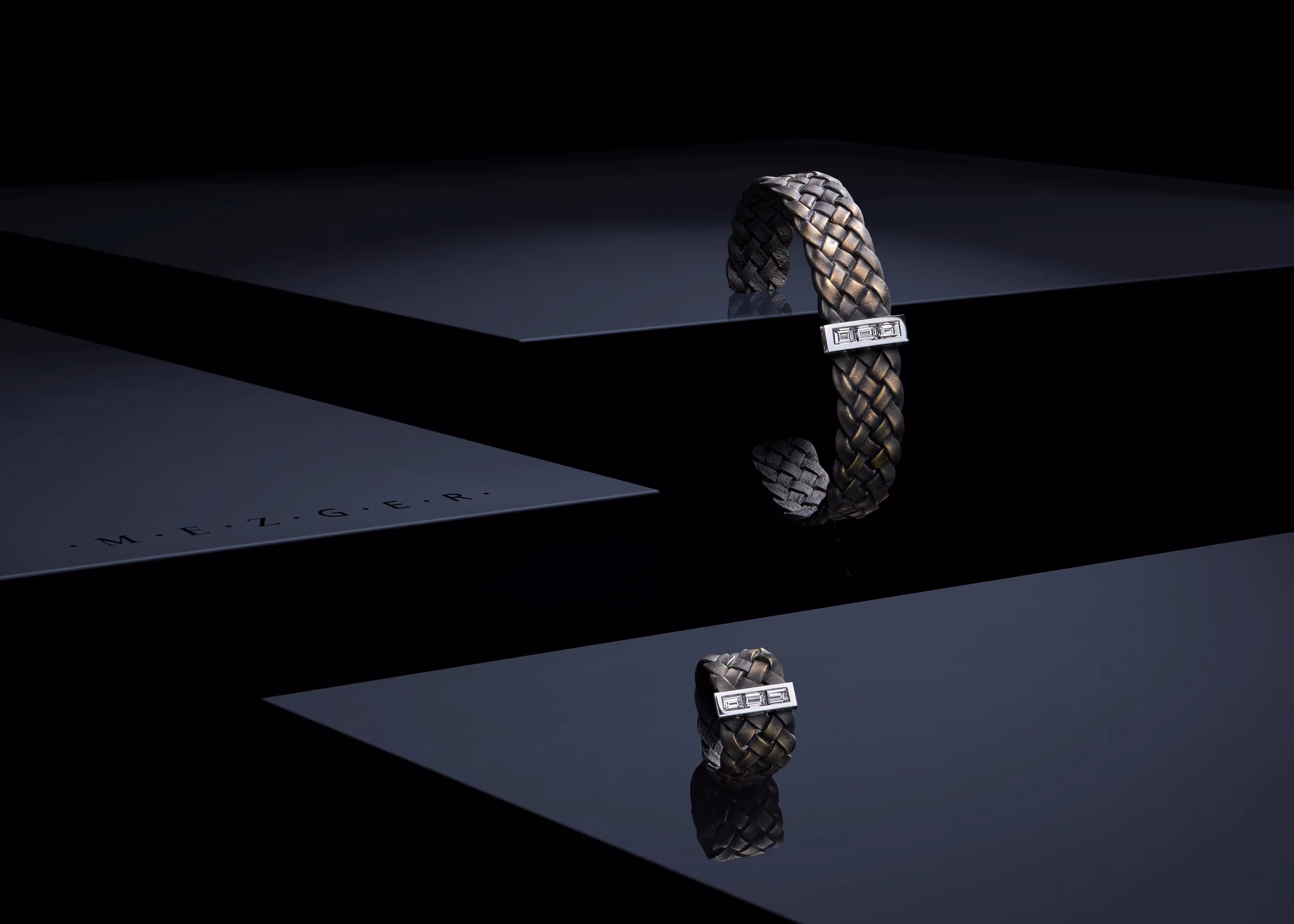 assortiment de bracelets brossé en or posé sur une surface noire brillante