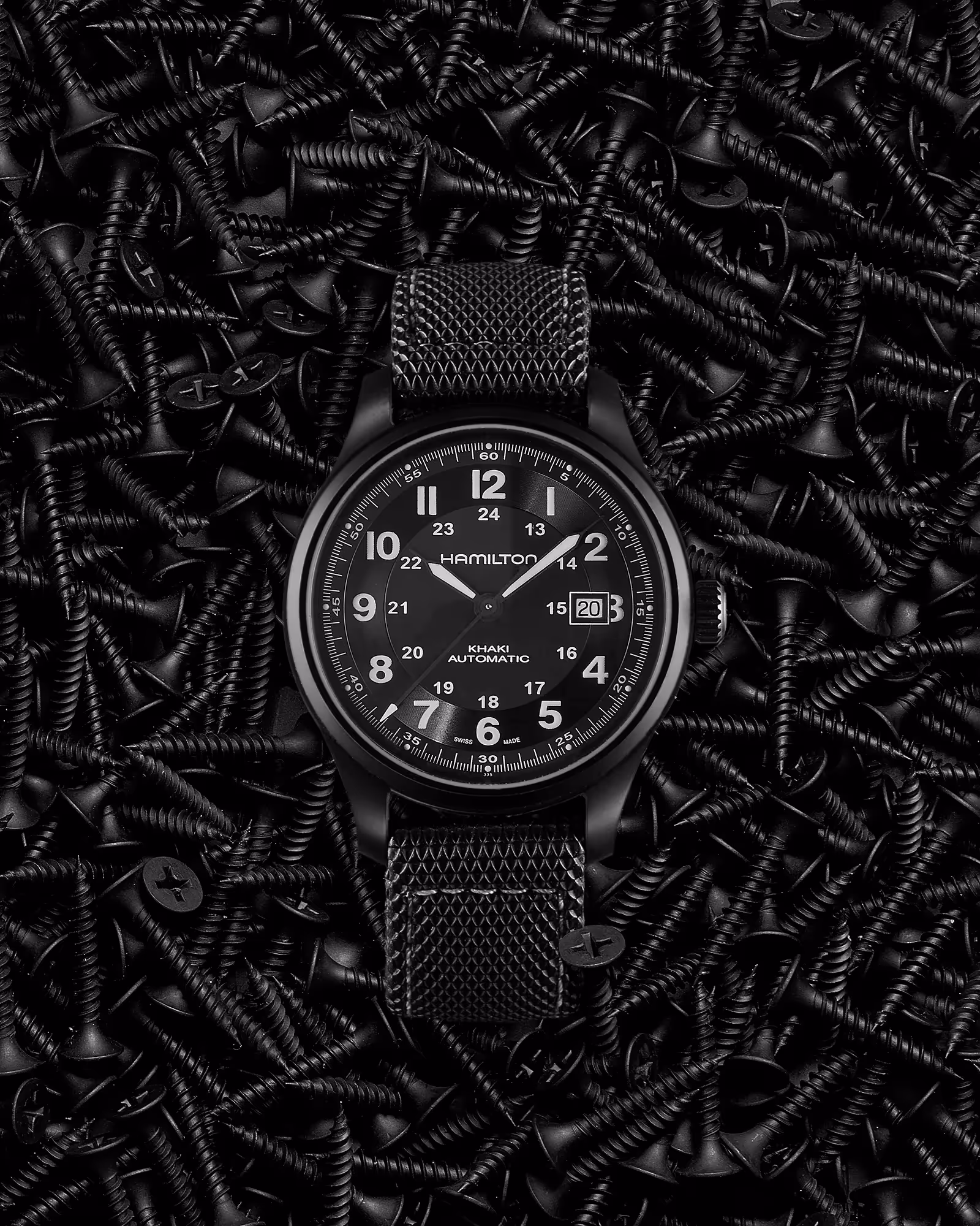 photo still life de la montre hamilton sur un fond décor de vis noires
