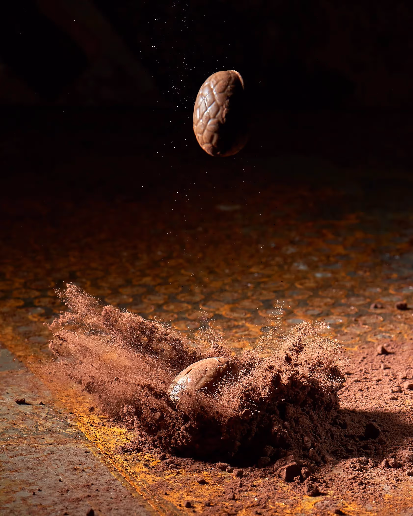 Oeuf de Pâque en chocolat qui tombe dans la poudre de cacao avec un effet de photografie à haute vitesse pour figer le mouvement