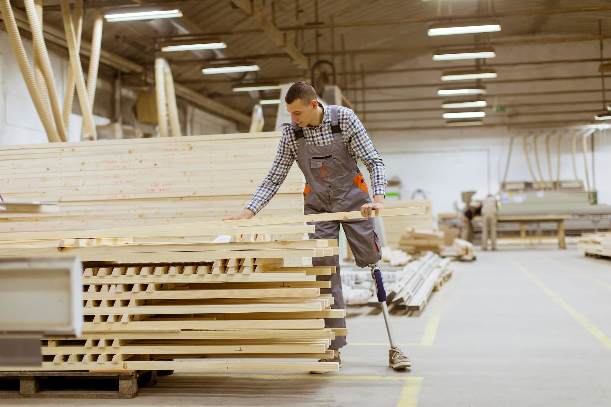  Man with prosthetic leg sorting boards in warehouse