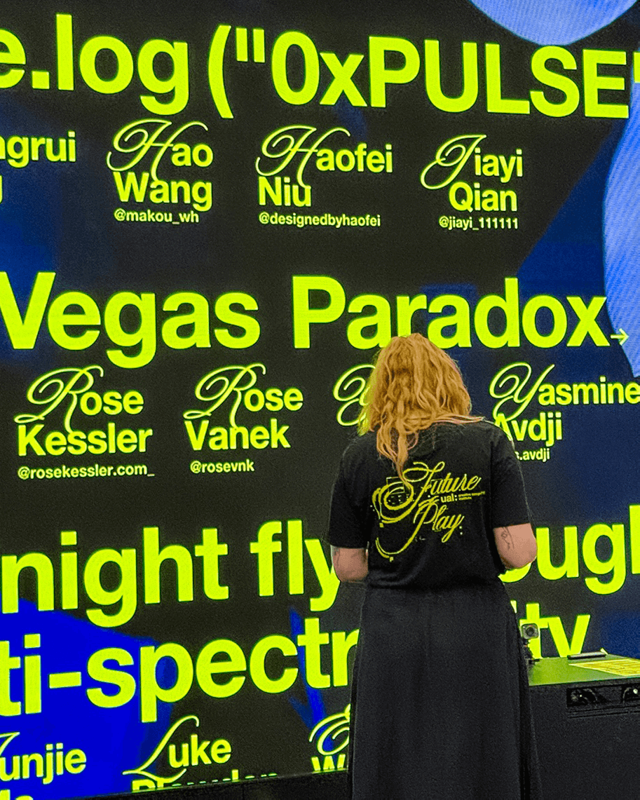 Person with curly blonde hair facing a black wall screen showing neon yellow text with names and social media handles related to '0xPULSE' and 'Vegas Paradox.'