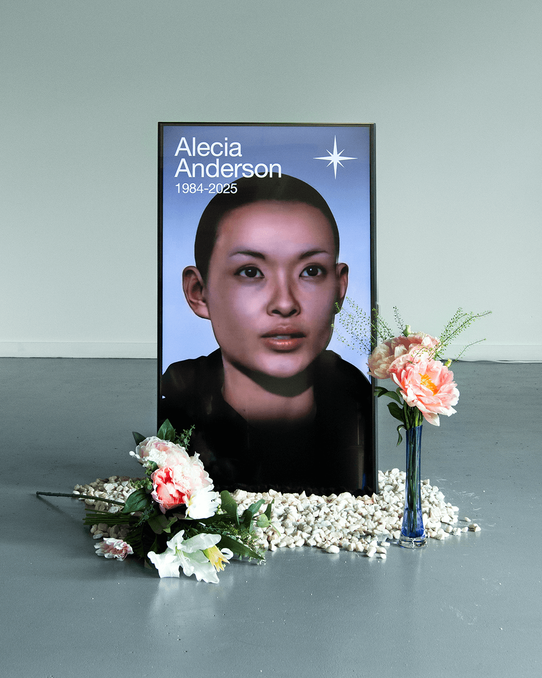 Memorial display with a digital portrait of Alecia Anderson (1984-2025) surrounded by white stones and flower arrangements.
