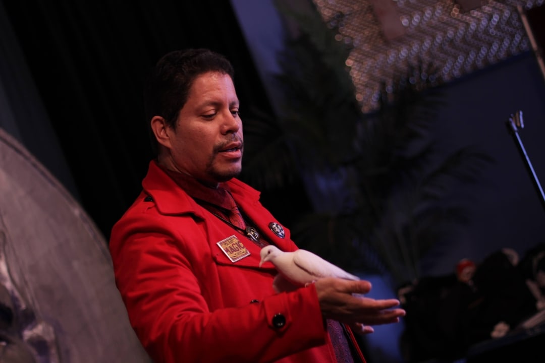 Magician Dr S holds a bird on stage